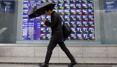 Asian-stocks - man walking in the rain in front of live rates board