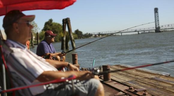 Retirees fish from a public dock on the Sacramento River in the Sacramento San Joaquin River Delta in Rio Vista, California