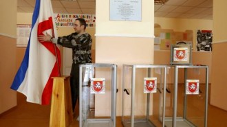 Election commission official installs Crimean flag during preparations for a referendum at the polling station in Simferopol