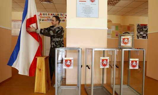 Election commission official installs Crimean flag during preparations for a referendum at the polling station in Simferopol