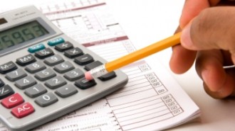 A man doing his taxes using a calculator and pencil on a white background