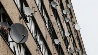 Satellite dishes are seen on the side of a block of flats in south London