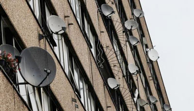 Satellite dishes are seen on the side of a block of flats in south London