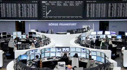 Traders are pictured at their desks in front of the DAX board at the Frankfurt stock exchange