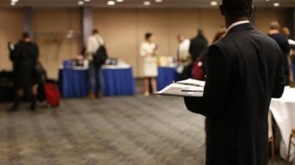 job seeker stands in a room of prospective employers at a career fair in New York City