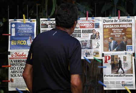 A man reads the front pages of various newspapers announcing Portugal's central bank's decision to rescue troubled lender Banco Espirito Santo (BES) in a 4.9 billion euro ($6.6 billion) recapitalisation in Lisbon in this August 4, 2014 file photo. REUTERS/Hugo Correia/Files