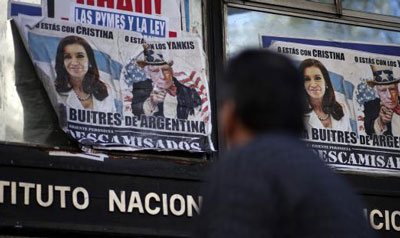 A man walks past posters with pictures of Argentina's President Cristina Fernandez de Kirchner and U.S. District Court for the Southern District of New York