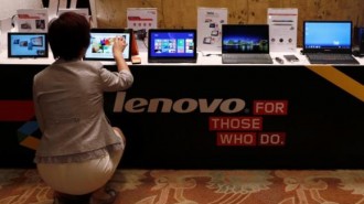 A woman tries a Lenovo tablet on display during a news conference announcing the company's annual results in Hong Kong