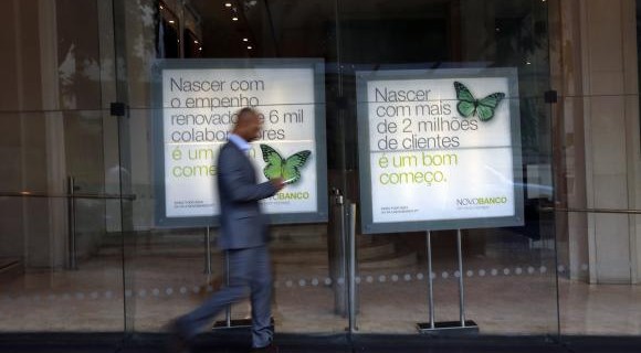 A man walks past Portuguese Novo Banco (New Bank) posters at its head office in Lisbon