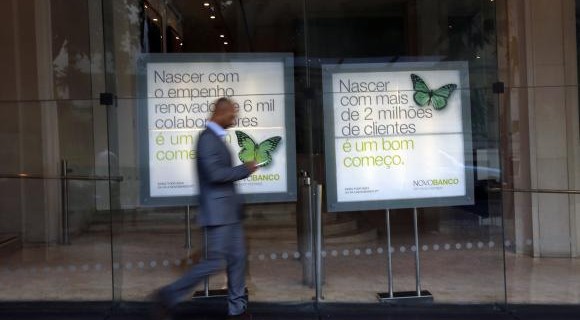 A man walks past Portuguese Novo Banco (New Bank) posters at its head office in Lisbon