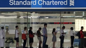 People queue up outside a Standard Chartered Bank branch before operation hours at the central business district in Singapore