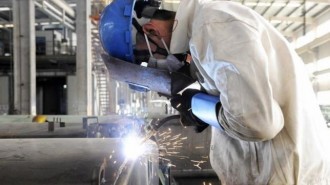 Employee welds the exterior of a vehicle along a production line at a factory in Qingdao