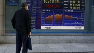 A man looks at an electronic board displaying the Nikkei average outside a brokerage in Tokyo