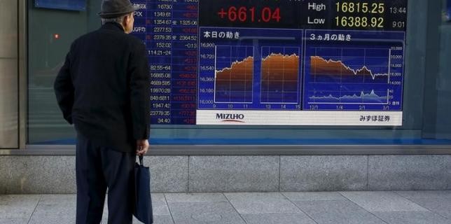 A man looks at an electronic board displaying the Nikkei average outside a brokerage in Tokyo