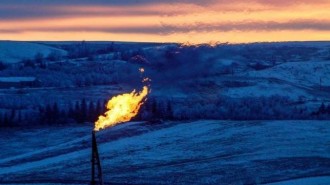 A natural gas flare on an oil well pad burns as the sun sets outside Watford City, North Dakota