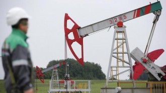 Worker looks at pump jack at oil field Buzovyazovskoye owned by Bashneft company north from Ufa