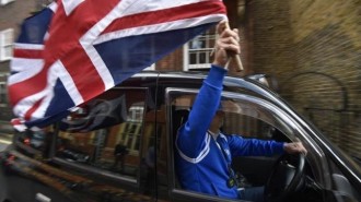 A taxi driver holds a Union flag, as he celebrates following the result of the EU referendum, in central London