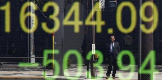 Businessman is reflected in an electronic board displaying Japan's Nikkei share average outside a brokerage in Tokyo
