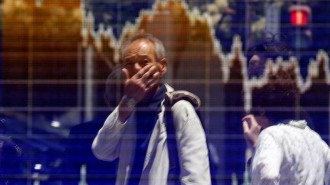 A man is reflected in an electronic board showing the graph of the recent fluctuations of the TOPIX outside a brokerage in Tokyo