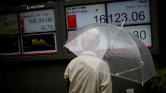 A man looks at an electronic board showing the recent exchange rate between Japanese yen against the U.S. dollar and Japan's Nikkei average outside a brokerage in Tokyo
