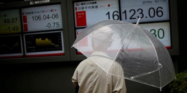 A man looks at an electronic board showing the recent exchange rate between Japanese yen against the U.S. dollar and Japan's Nikkei average outside a brokerage in Tokyo
