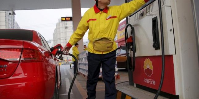 A gas station attendant pumps fuel into a customer's car at PetroChina's petrol station in Beijing