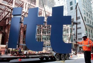 A worker guides part of a Deloitte sign before its installation on a new office building in downtown Toronto