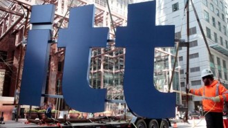 A worker guides part of a Deloitte sign before its installation on a new office building in downtown Toronto