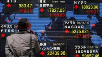 A man looks at an electronic board showing the stock market indices of various countries outside a brokerage in Tokyo