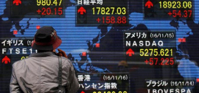 A man looks at an electronic board showing the stock market indices of various countries outside a brokerage in Tokyo