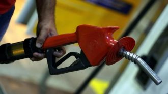 An employee holds a gas pump at a petrol station in Sao Paulo