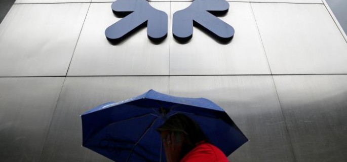 A woman shelters under an umbrella as she walks past a branch of RBS in the City of London