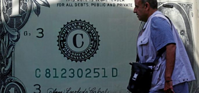 A man walks past a currency exchange bureau advertisement showing an image of the U.S. dollar in Cairo