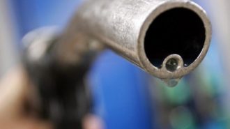 A motorist holds a fuel pump at a Gulf petrol station in London