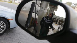 A fuel pump assistant fills cars with petrol at Budaiya Fueling Station west of Manama, Bahrain